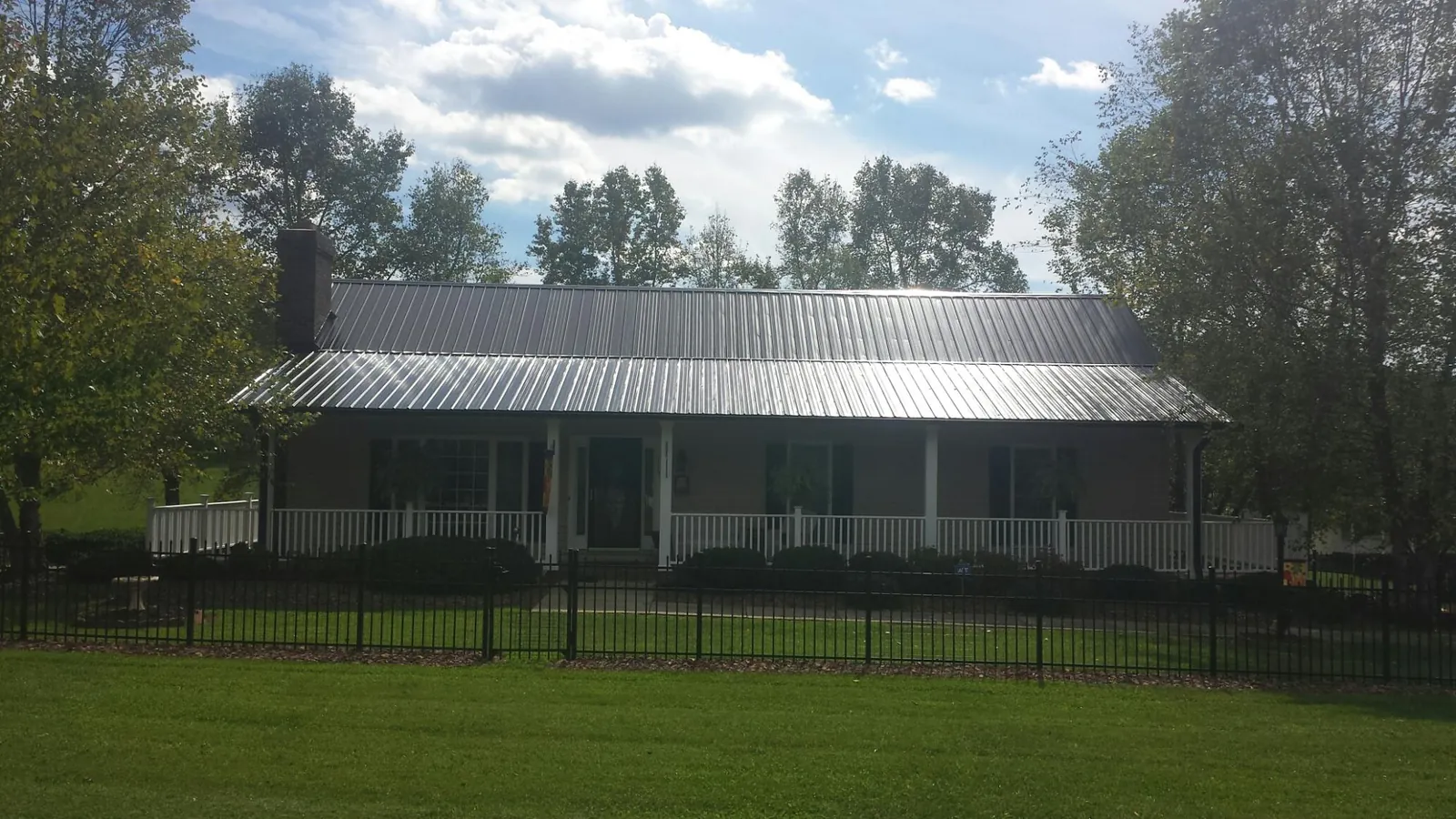 Gray metal roof on a brick ranch with a full width front porch — Gutter Guard Installation work by our crew in Iona